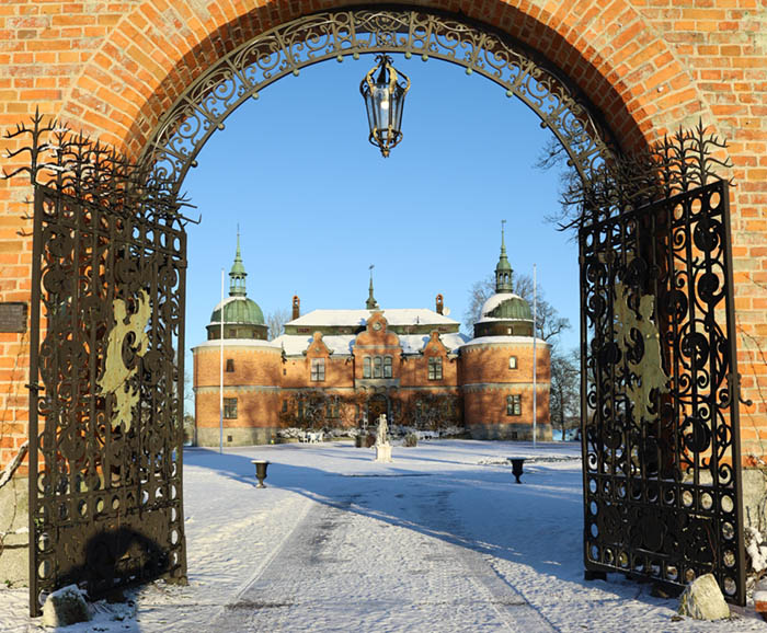 Portalen med smidesgrindar och slottet i bakgrunden