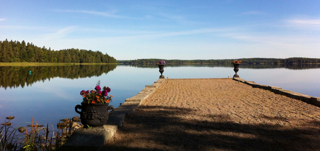 Stenbrygga med spegelblankt vatten över sjön Båven
