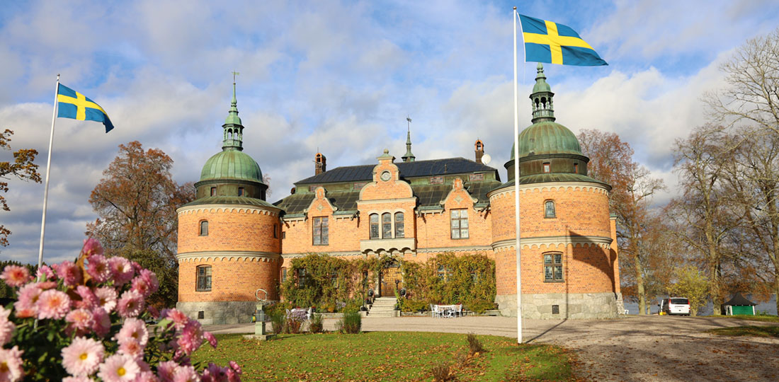 Rockelstad slott med svenska flaggor och blommor i förgrunden