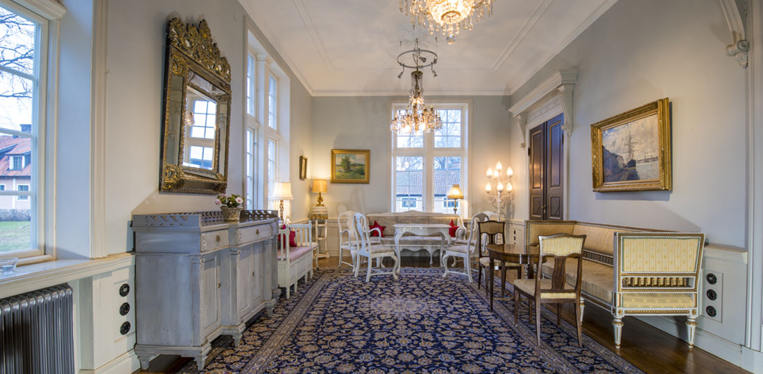 Förmaket med stor blå antik matta, guldspegel och gustaviansk soffa
