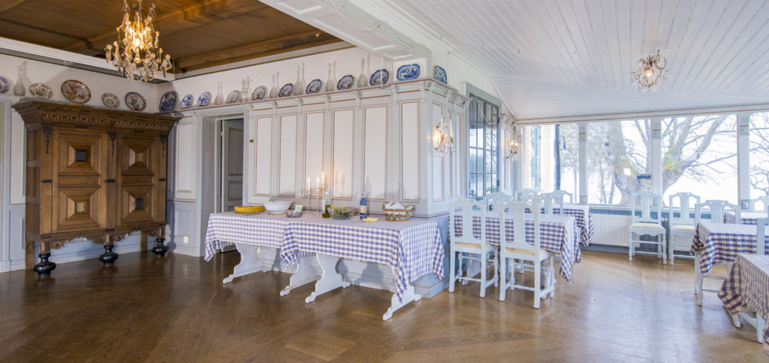 Matsal med barockskåp och höga paneler, ekgolv och glasveranda